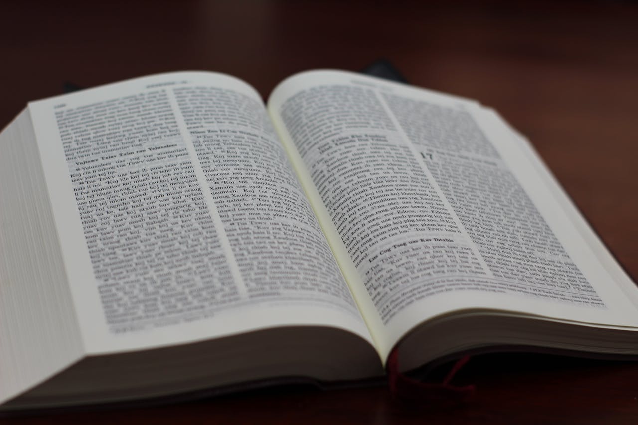 Close-up of an open Bible on a wooden table, showing text and details.